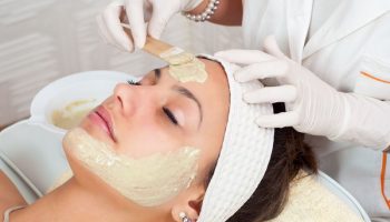 cosmetologist applying face mask on a woman