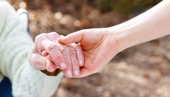 caregiver holding hands with old lady