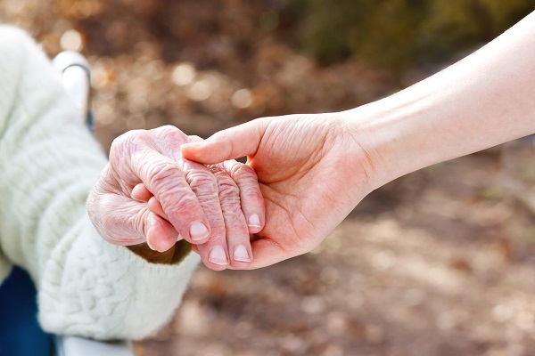 caregiver holding hands with old lady